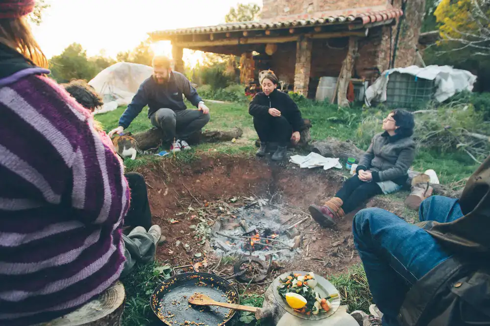 A group of people sitting around an outdoor fire pit enjoying a wild food feast