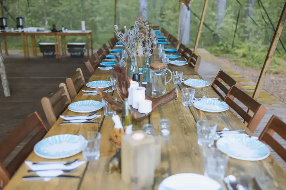 A long rustic dining table set in a woodland clearing