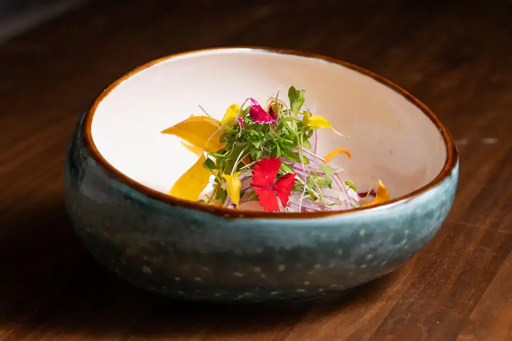 A beautifully plated dish featuring wild herbs and earthy ingredients on rustic ceramics